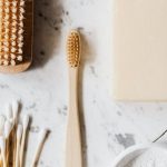 Natural Cleaning Solutions - Top view composition of wooden cleaning brush and soap and toothbrush and tooth powder and cotton swab placed on marble surface with line chip