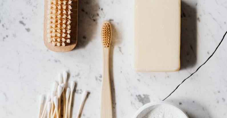 Natural Cleaning Solutions - Top view composition of wooden cleaning brush and soap and toothbrush and tooth powder and cotton swab placed on marble surface with line chip